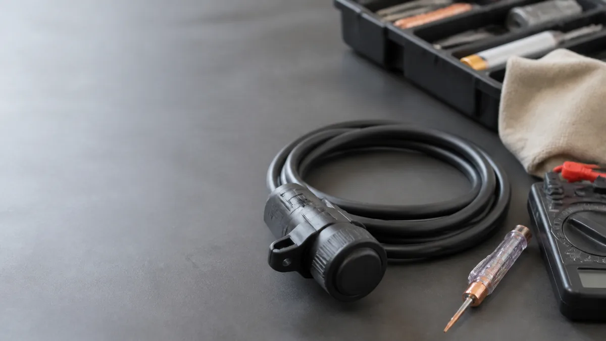 Covered trailer connector cable beside electrical test tools on a bench