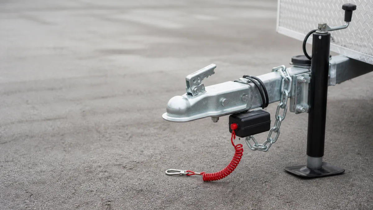 Trailer coupler with breakaway pull switch and coiled lanyard while parked